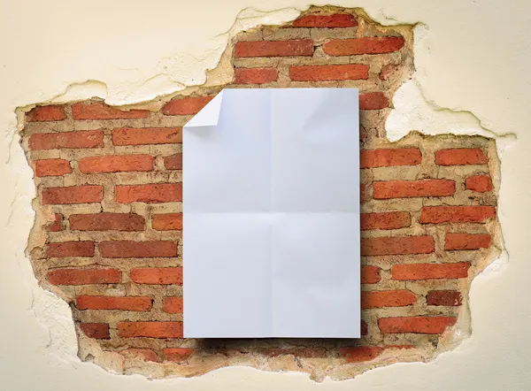 Folded white paper on damaged brick wall background. — Stock Photo, Image