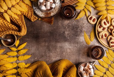 Mumlu çerçeve, kurabiyeler, sonbahar yaprakları, kahverengi arka planda marşmelovlu kakao. Düz konum, üst görünüm, kopyalama alanı.