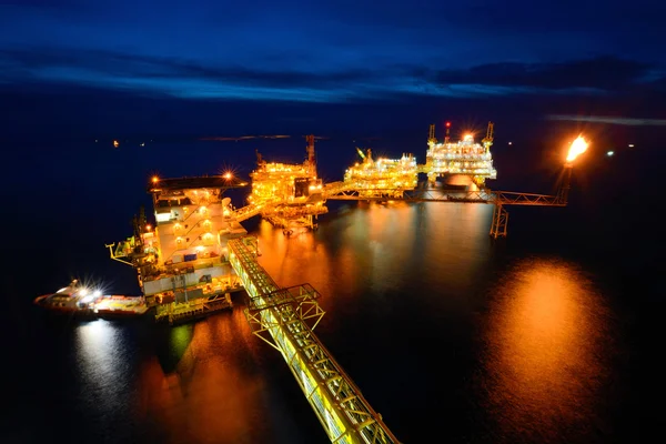 Az ellátás hajó éjjel dolgozik a nagy tengeri fúrótorony — Stock Fotó