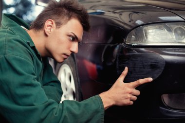 Close-up of damaged car inspected by mechanic clipart