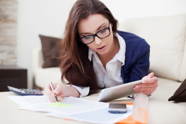 Young woman working from home using her digital tablet clipart