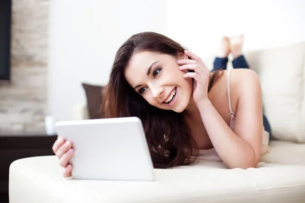 Glad kvinna med hennes digital tablet på soffan — Stockfoto