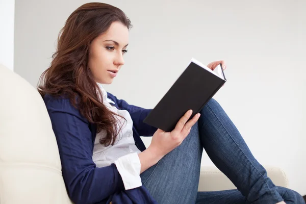 Mujer joven leyendo un libro en casa — Foto de Stock