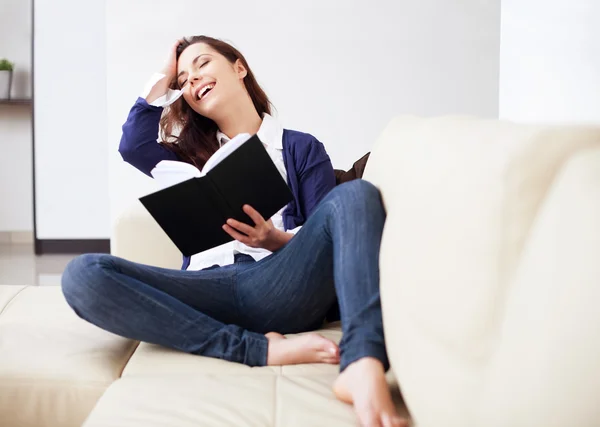 Joyeux jeune femme lisant un livre à la maison — Photo