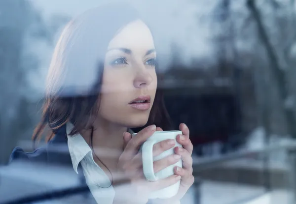 Mujer joven mirando por la ventana — Foto de Stock