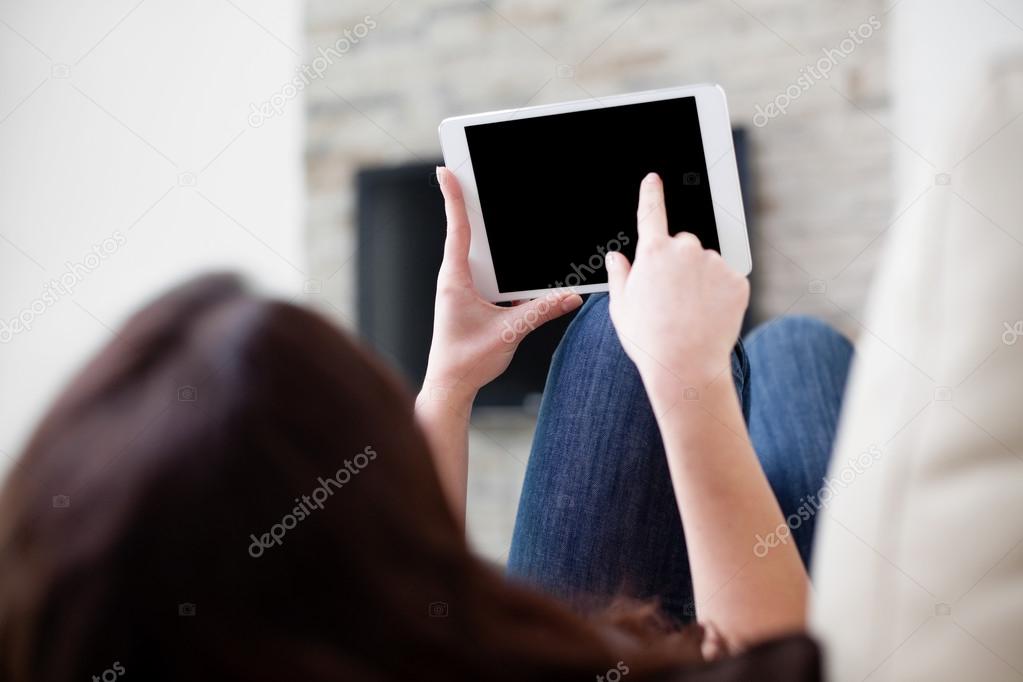 Woman using digital tablet on couch