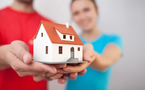 Pareja joven sosteniendo casa miniatre — Foto de Stock