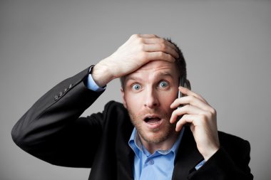 Shocked businessman talking on the phone clipart