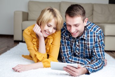 genç bir çift dijital tablet ile yerde yatarken
