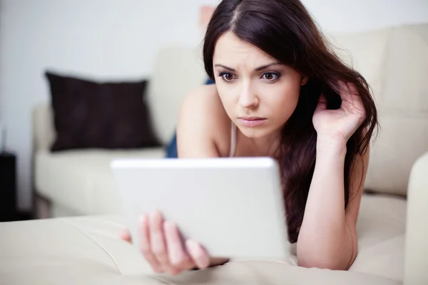 Mulher triste deitada no sofá com tablet — Fotografia de Stock