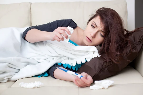 Sick woman lying with thermometer — Stock Photo, Image