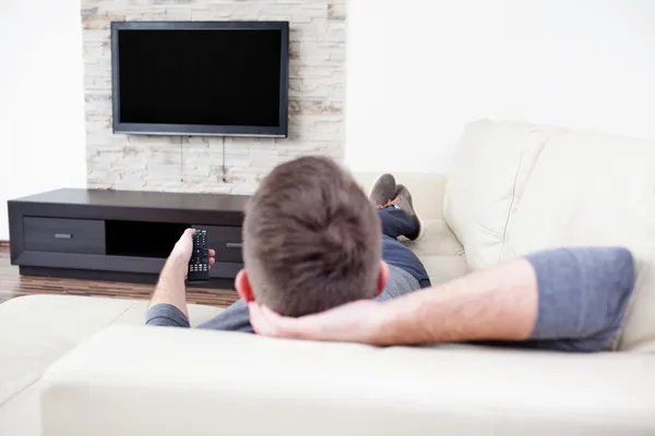 Homme célibataire sur le canapé regarder la télévision — Photo