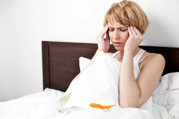 Baş ağrısı ile yatakta yatan hasta bir kadın — Stok fotoğraf