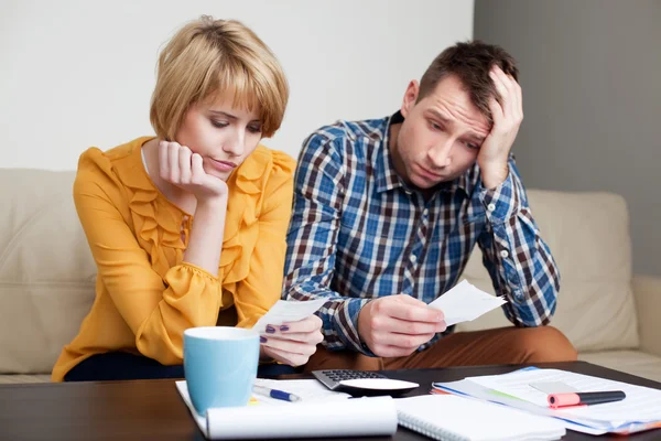 Trauriges junges Paar bezahlt Rechnungen. — Stockfoto