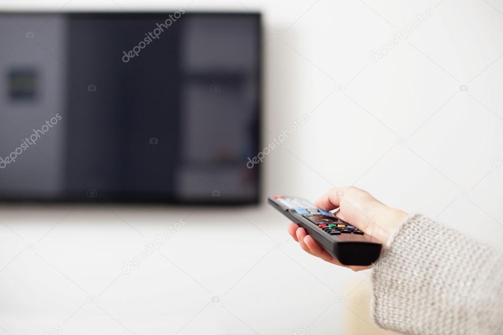 Female hand holding TV Remote Control