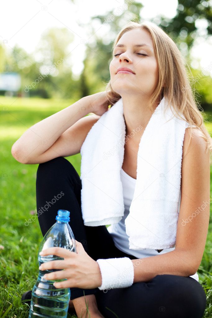 Young woman drinking water after training