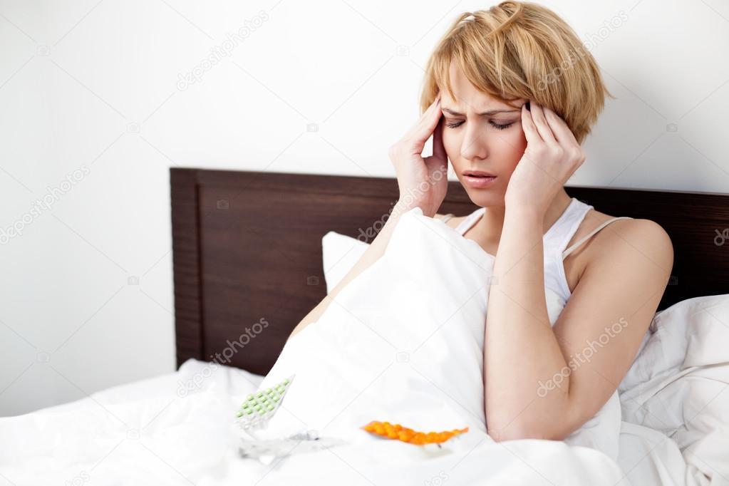 Sick woman lying in bed with headache