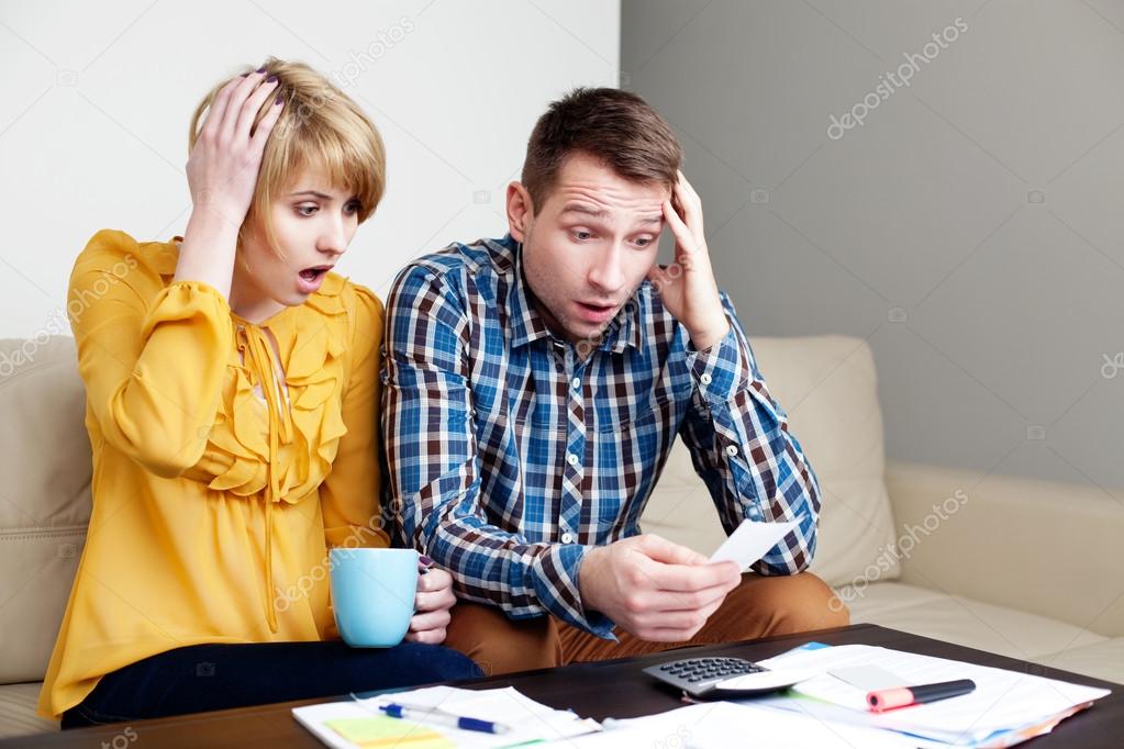 Shocked couple paying bills.