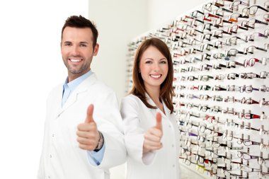 Two happy optician, optometrist showing thumbs up