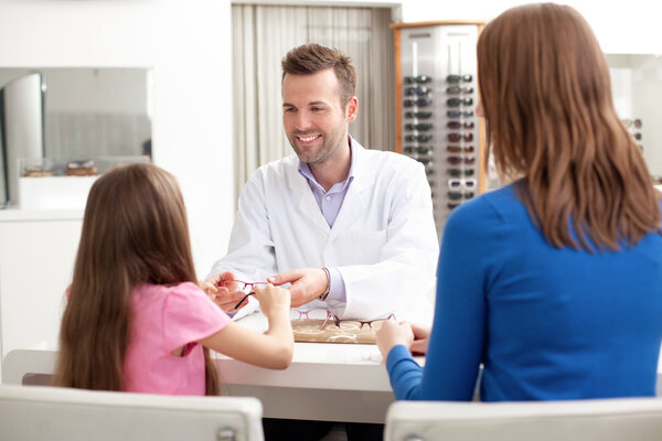 Optician giving glasses to try