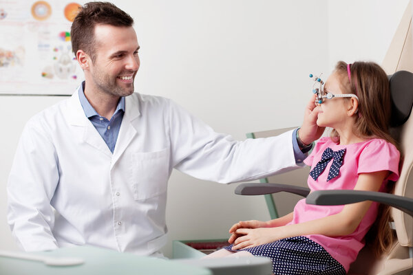 Eye doctor, optometrist working with young girl