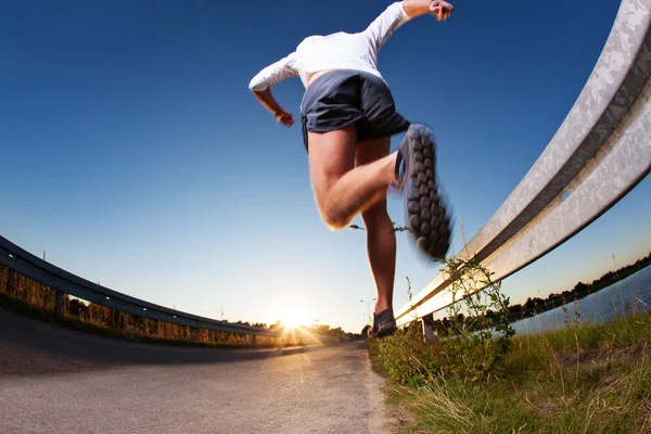 Homem correndo na estrada durante o pôr do sol — Fotografia de Stock