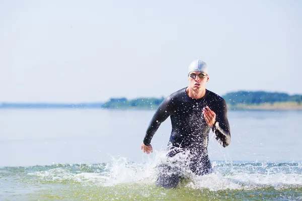 Triatleet uit het water loopt — Stockfoto