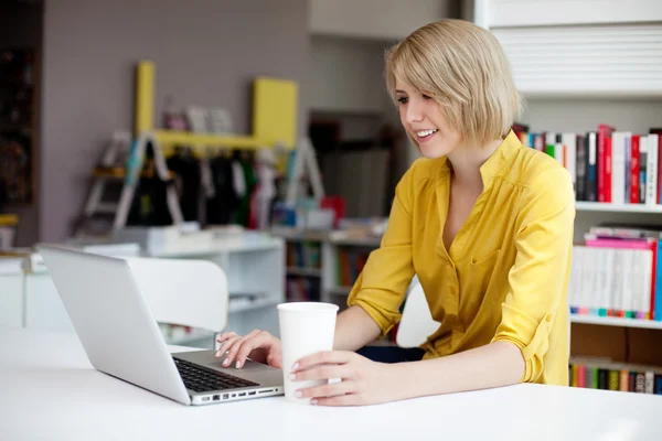 Happy female manager working on laptop in bookshop — Stock Photo, Image