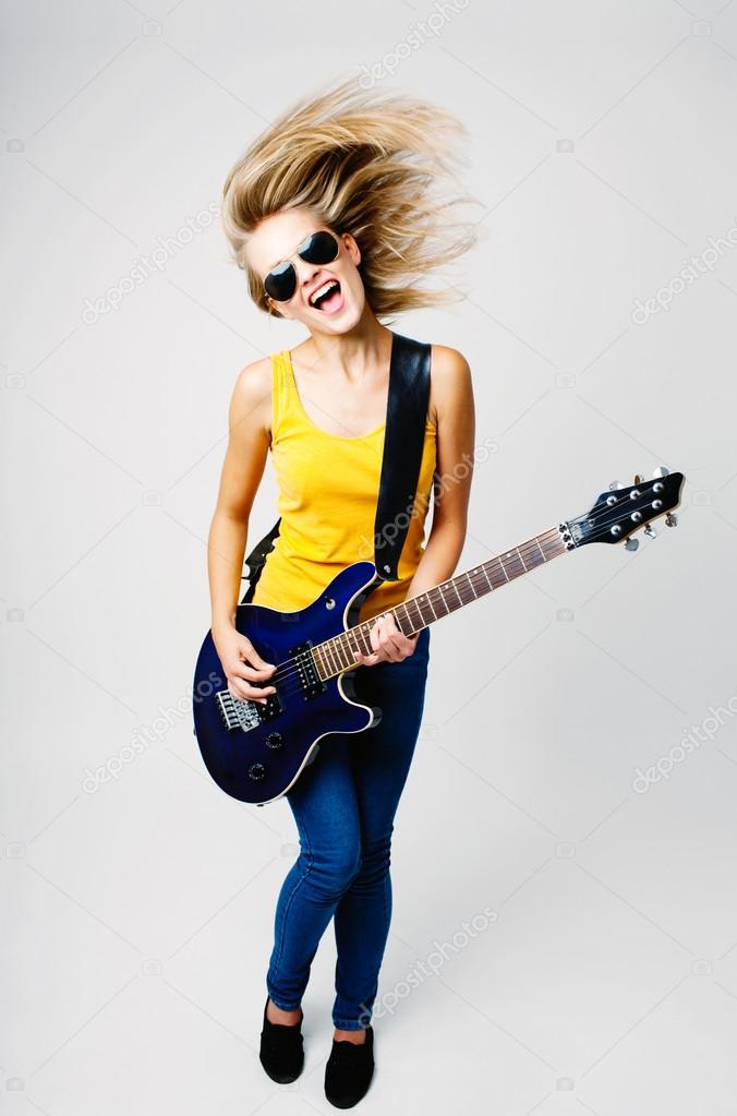 Young woman singing and playing on electric guitar