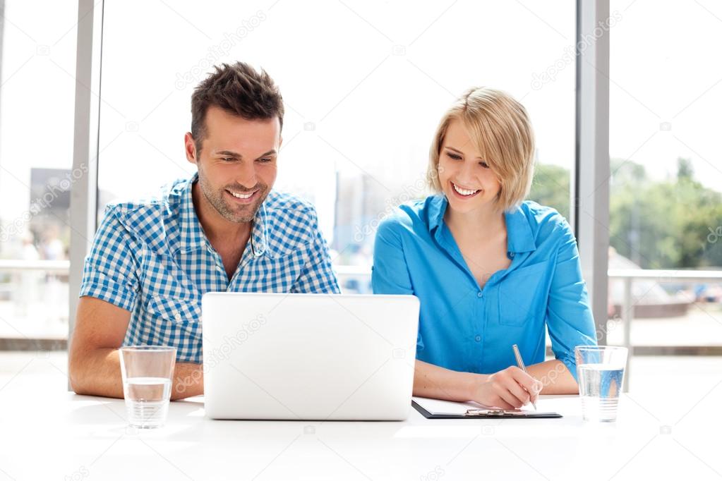 Happy business partners working on laptop