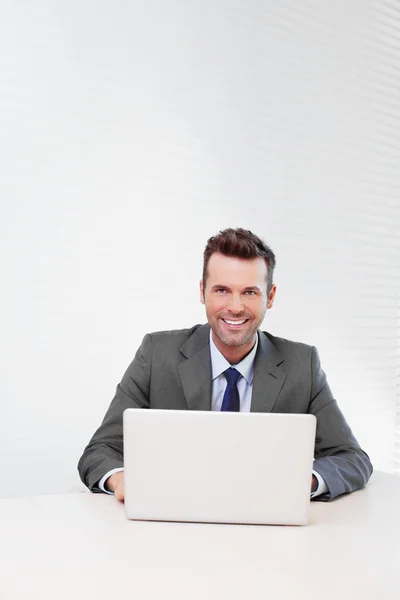 Glücklicher Geschäftsmann, der im Büro am Laptop arbeitet — Stockfoto