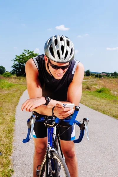 Triathlon ciclista mensagens de texto no smartphone — Fotografia de Stock
