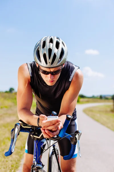 Triathlonfahrer navigiert auf Smartphone — Stockfoto