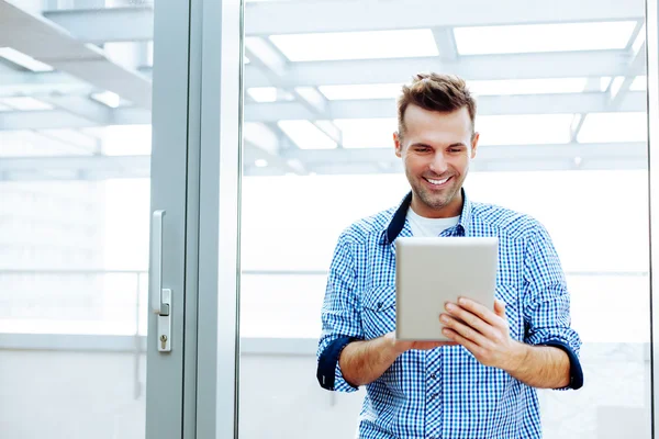 Usmívající se mladý muž, který držel digitální tabletu — Stock fotografie