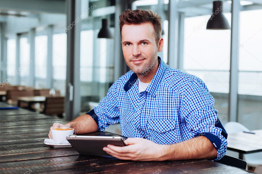 Man enjoying coffee and using tablet