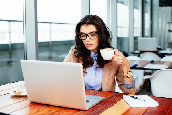 Woman holding cup and browsing net — Stock Photo, Image