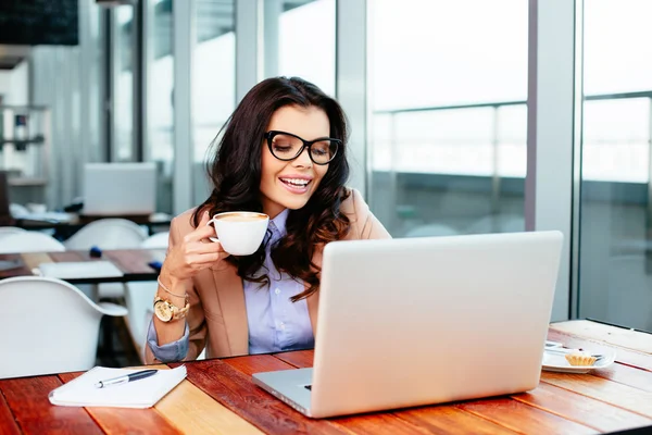 Kvinna dricker kaffe och använder bärbar dator — Stockfoto