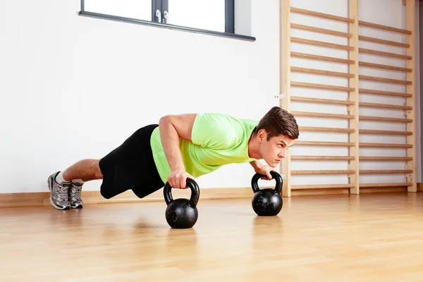 Sportler macht Liegestütze auf Kettlebells — Stockfoto