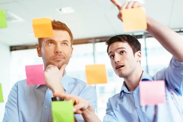 Businessmen discussing ideas on sticky notes — Stock Photo, Image