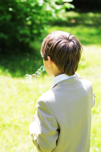 Garçon en uniforme scolaire avec bulles de savon — Photo