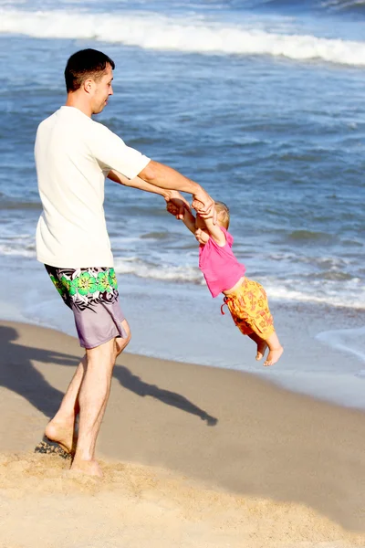 Papa avec un enfant jouant sur la rive de la mer — Photo