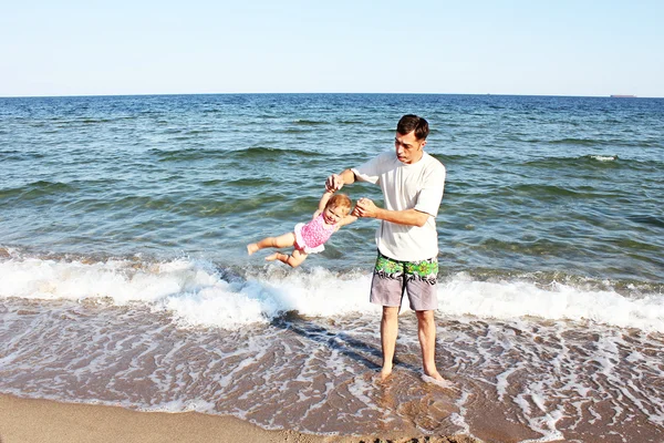 Vader met een kind spelen op de oever van de zee — Stockfoto