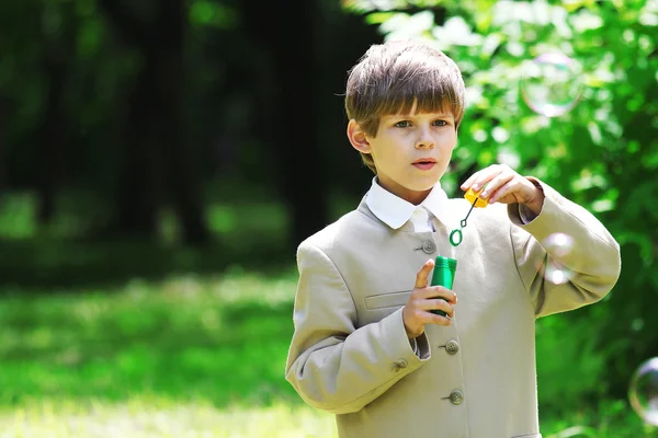 Menino de uniforme escolar com bolhas de sabão — Fotografia de Stock
