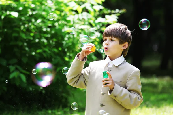 Menino de uniforme escolar com bolhas de sabão — Fotografia de Stock