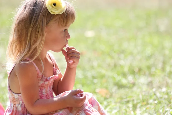 Beautiful little girl with lipstick on nature — Stock Photo, Image