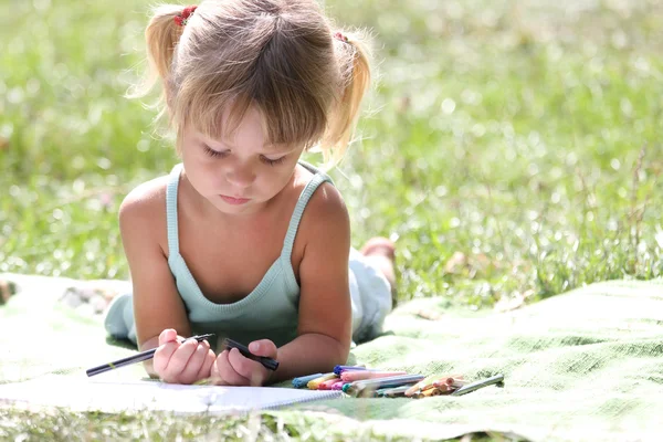 Красивая маленькая девочка рисует на природе — стоковое фото