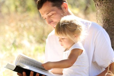 Young father with his daughter reads the Bible