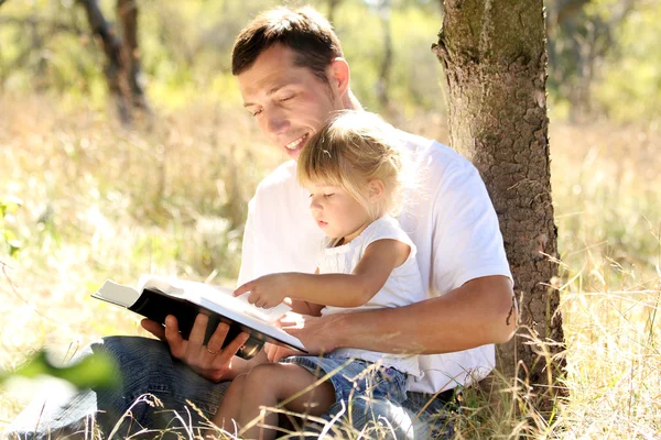 El joven padre con su hija lee la Biblia — Foto de Stock