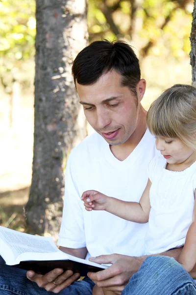 Young father with his daughter reads the Bible — Stock Photo, Image