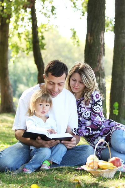 Молодая семья с ребенком, читающим Библию — стоковое фото
